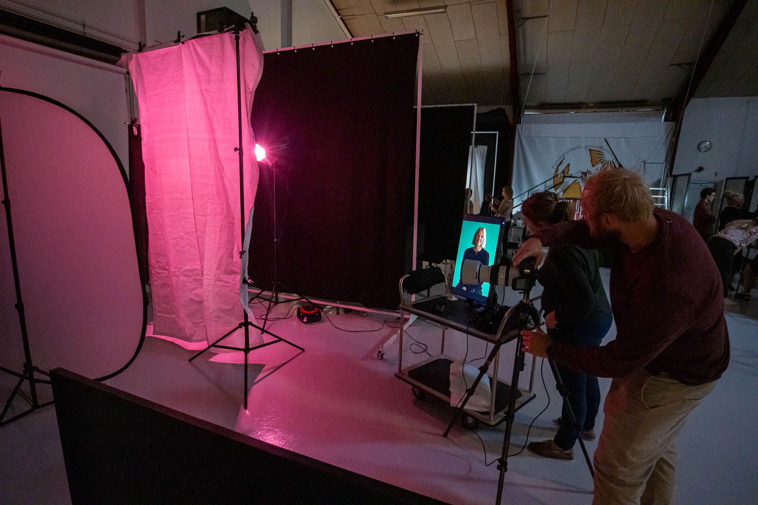 Professional photography studio setup with pink lighting and various equipment arranged for a fashion shoot.
