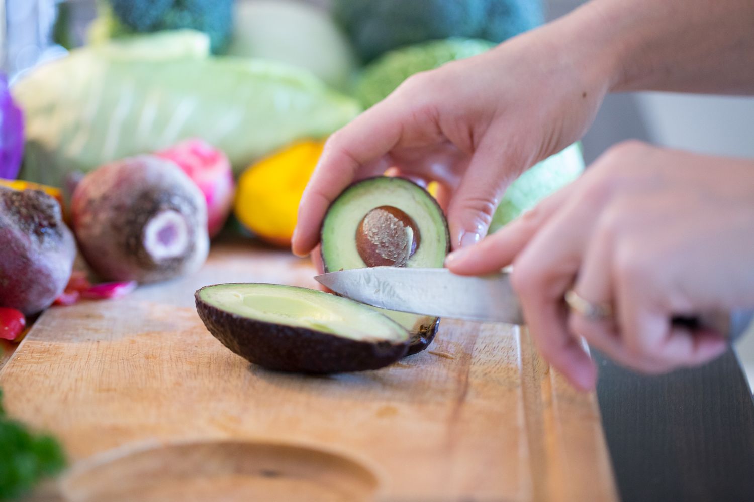 Close-up shots of hands cutting fresh avocados and vegetables on wooden cutting boards.