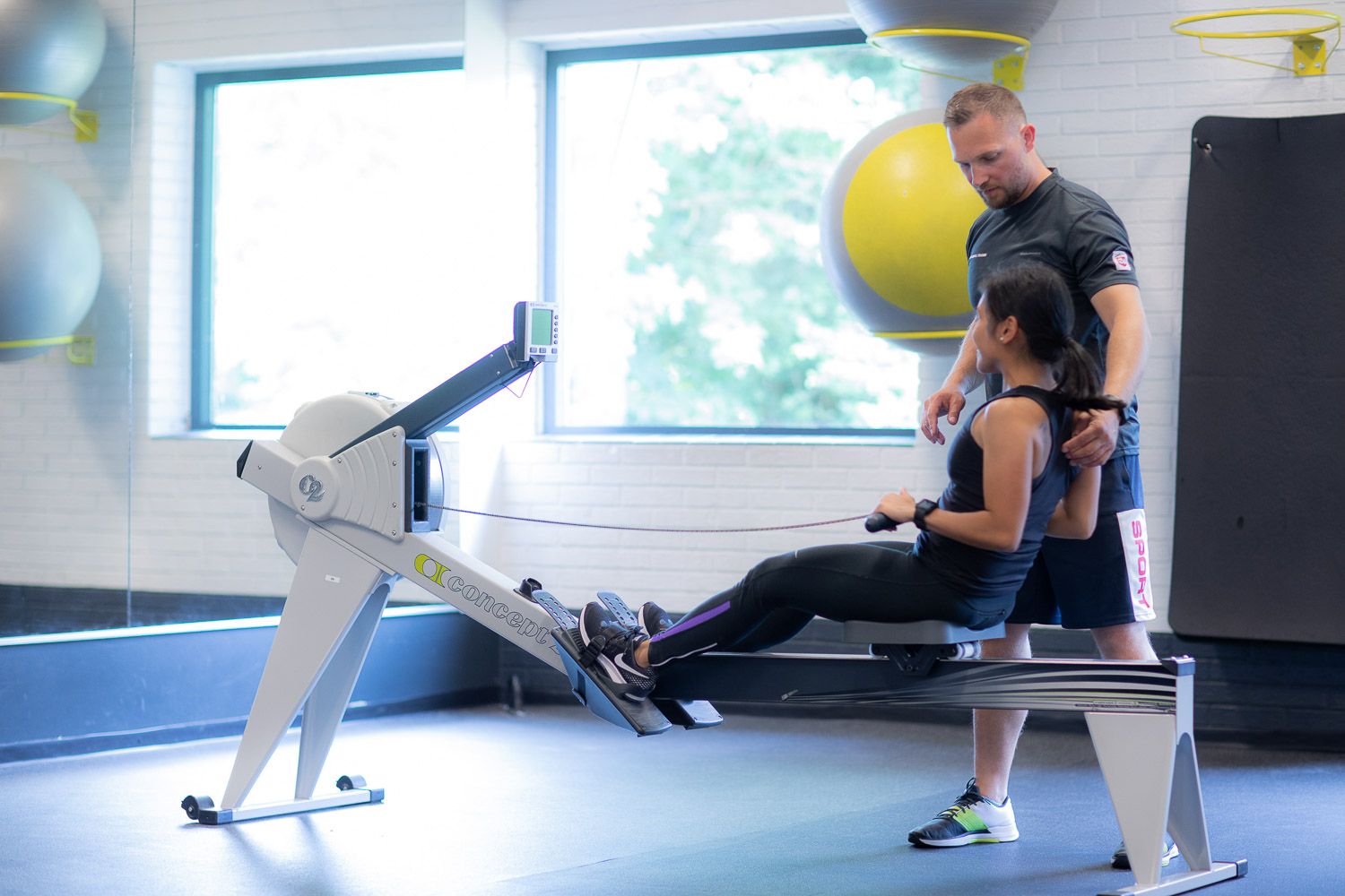 Exercise instruction session in progress at modern fitness facility with large windows.