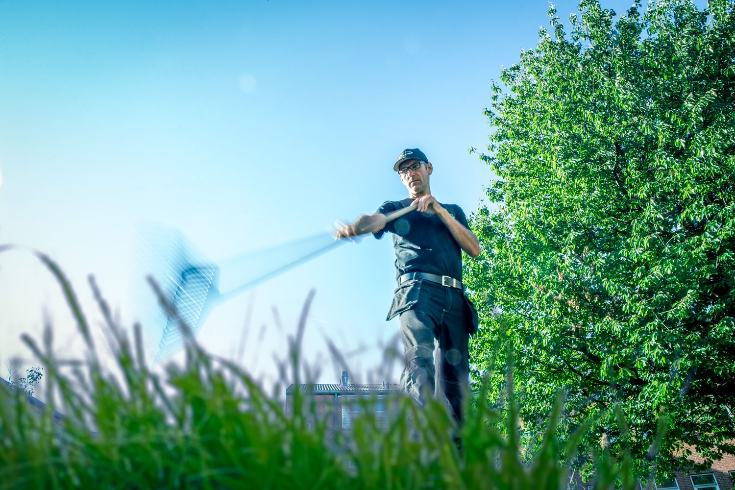 Pest control specialist applying treatment around outdoor garden area.