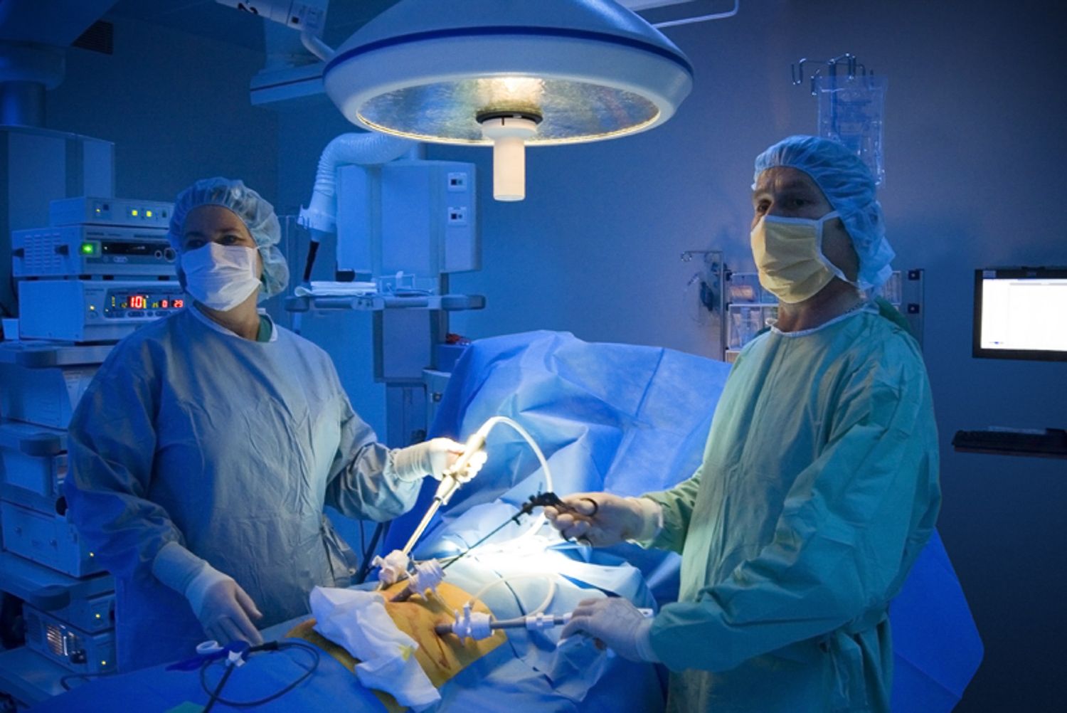 Operating room scene with medical professionals performing surgery under bright surgical lights.