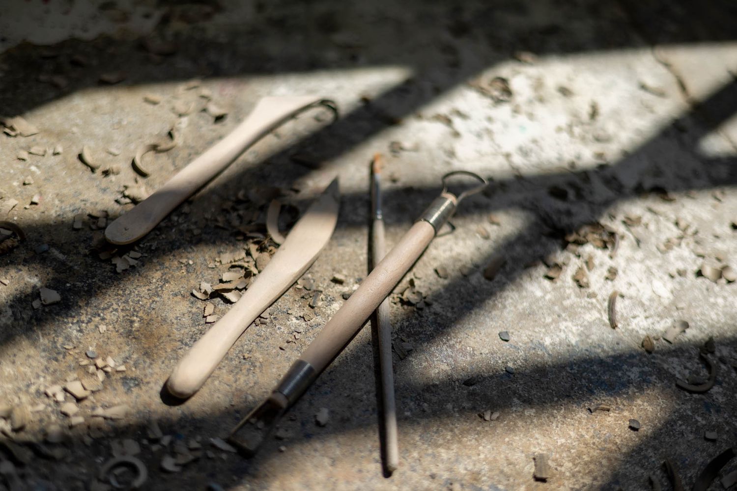 Dramatic shadows cast across textured clay and pottery tools.