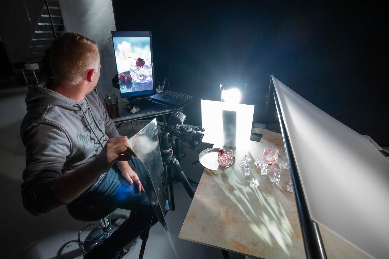 Photography workspace with monitors displaying images and professional lighting equipment.