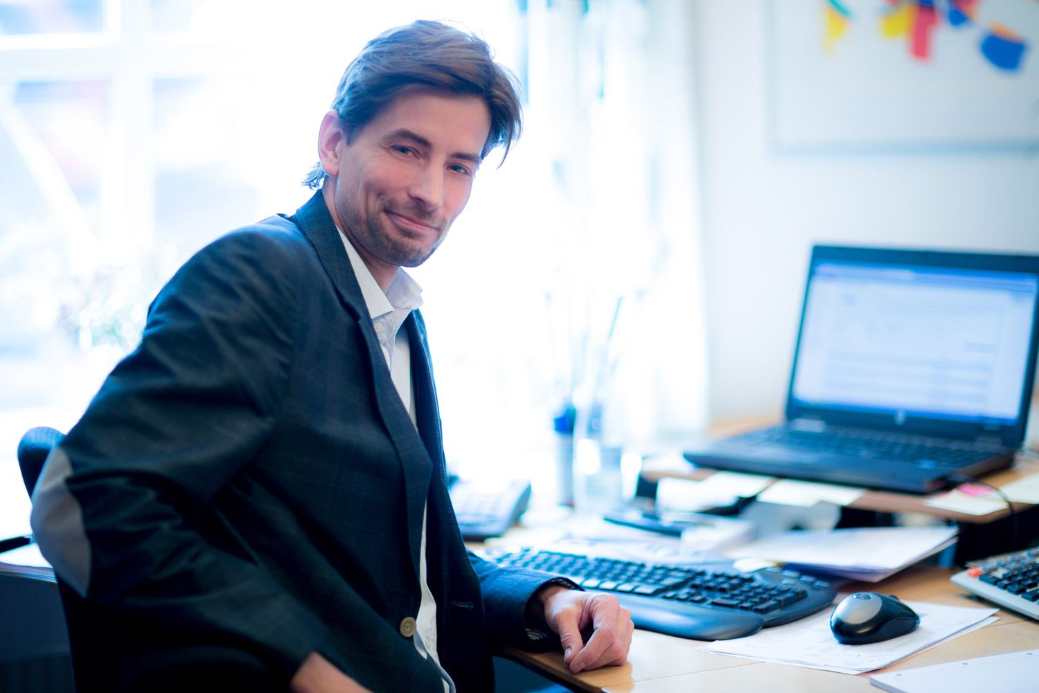 Business professionals working at modern office desks with computers in bright workspace.