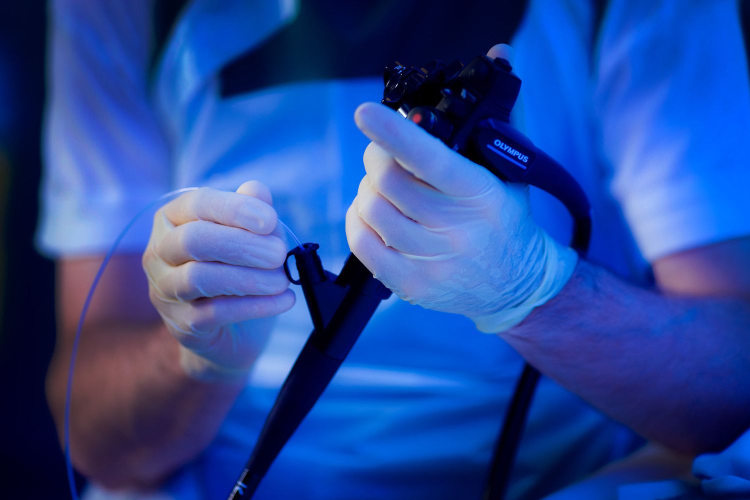 Close-up of surgical instruments being handled during medical procedure under blue lighting.