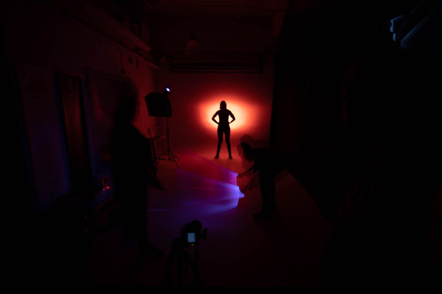 Dark studio space illuminated with dramatic red lighting during a photo session.