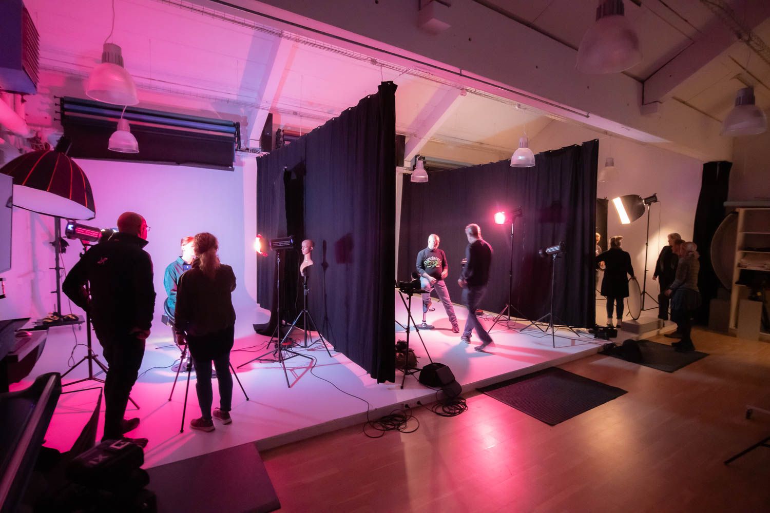 Behind-the-scenes photo shoot setup with dramatic pink lighting in a studio space.