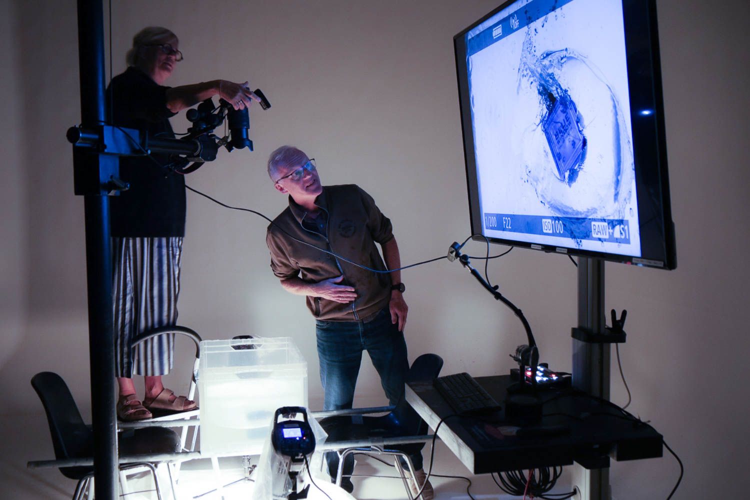 Studio photography session showing monitors and lighting equipment in a dark room.