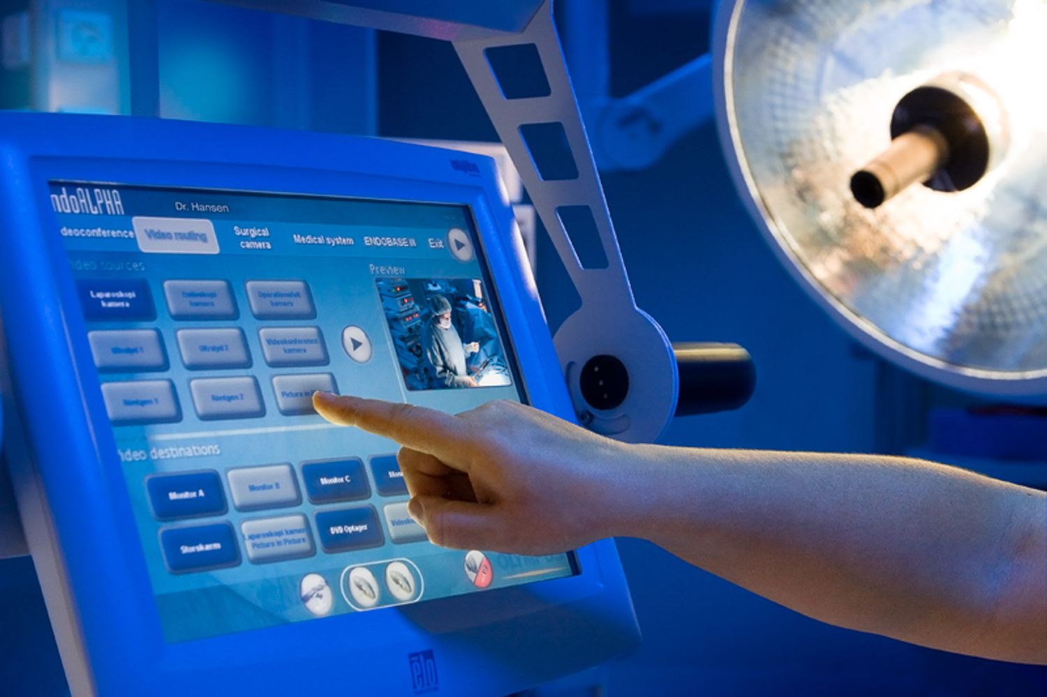 Operating room with digital displays and surgical equipment under blue lighting.