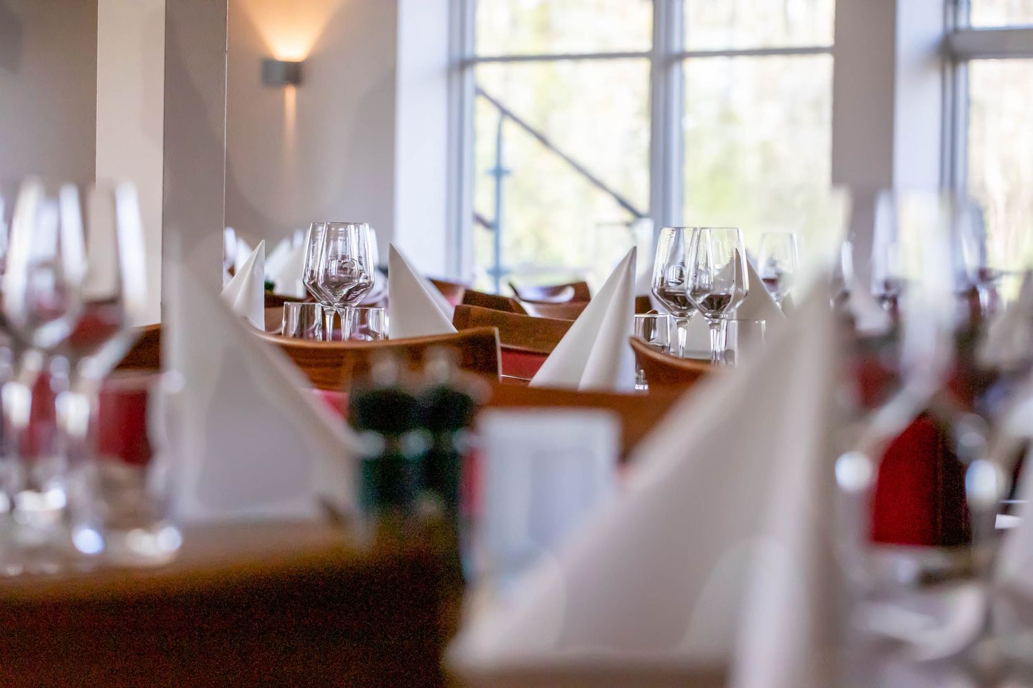 Elegant restaurant interior with white tablecloths and natural lighting streaming through large windows.
