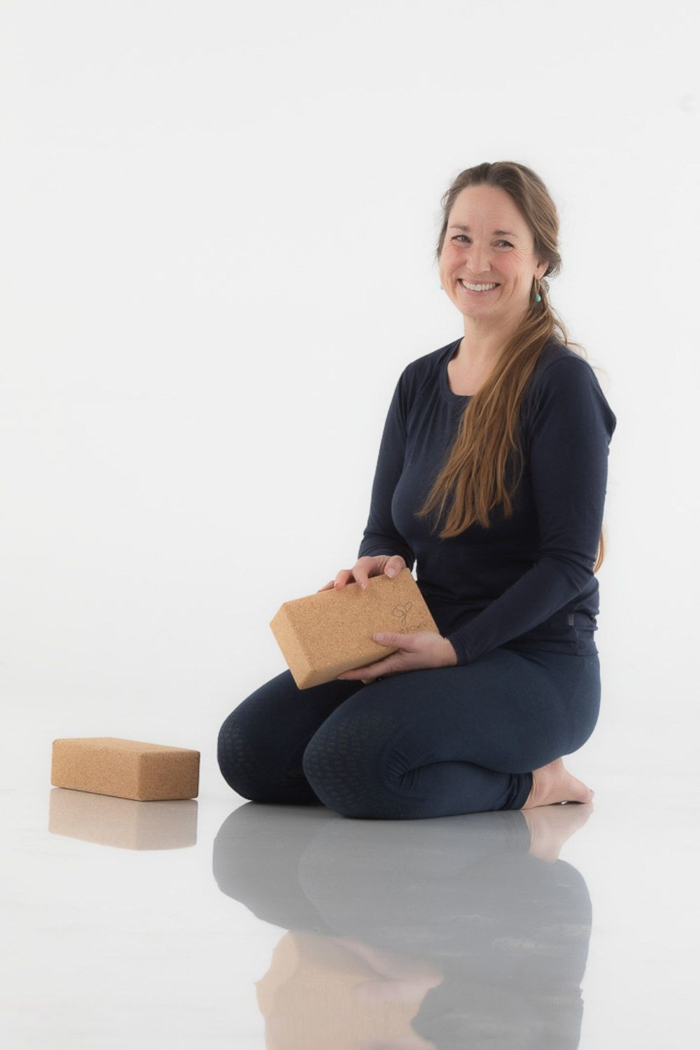 Person in navy outfit interacting with cork blocks while sitting on reflective surface.