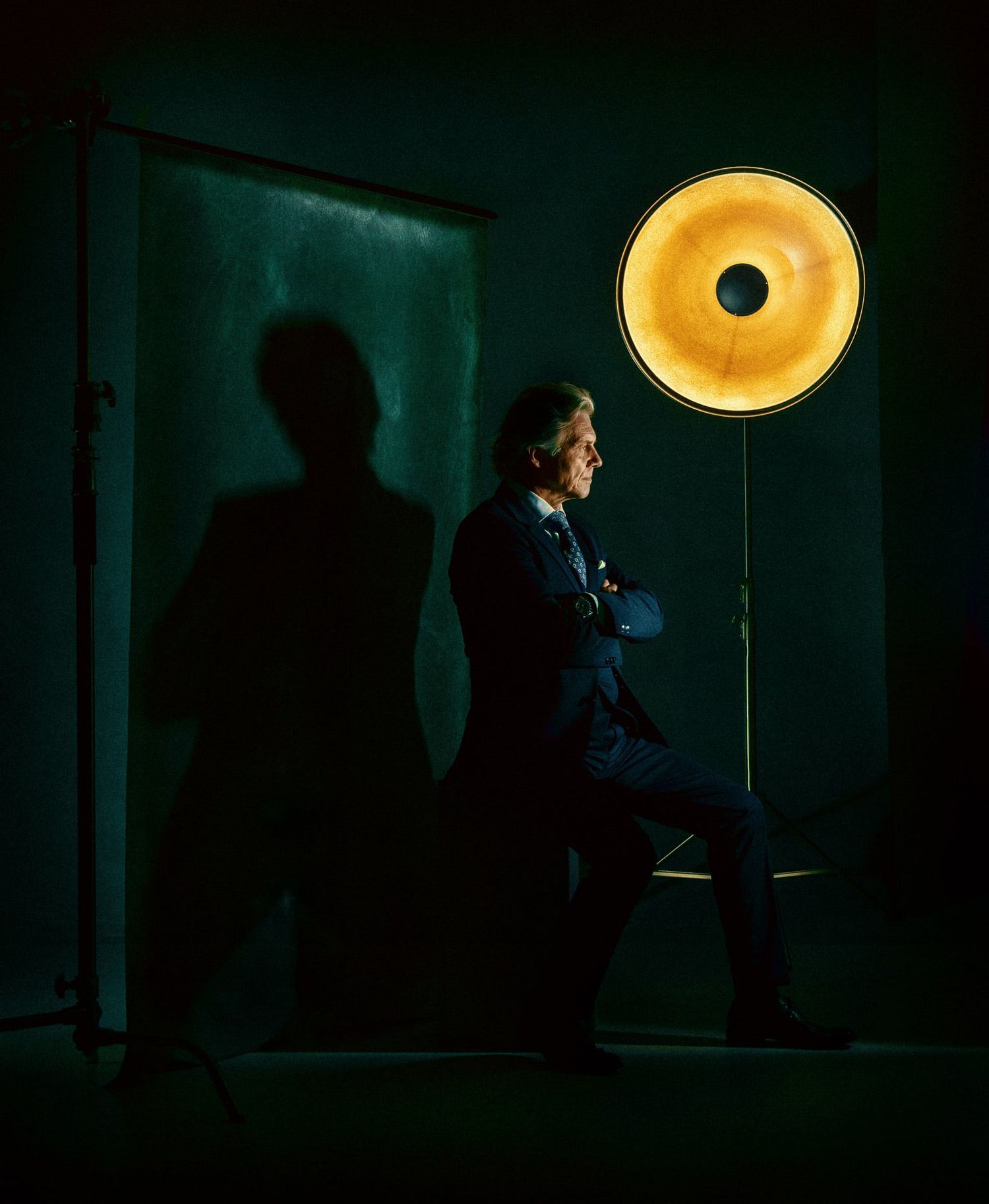 Artistic studio photo with dramatic golden ring light creating moody silhouette effect.