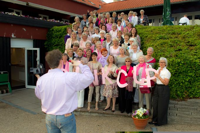 Large group photo being taken outdoors near a building entrance.