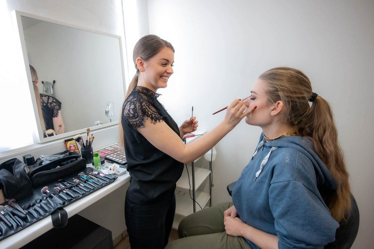 Professional makeup application being done in a bright studio setting.
