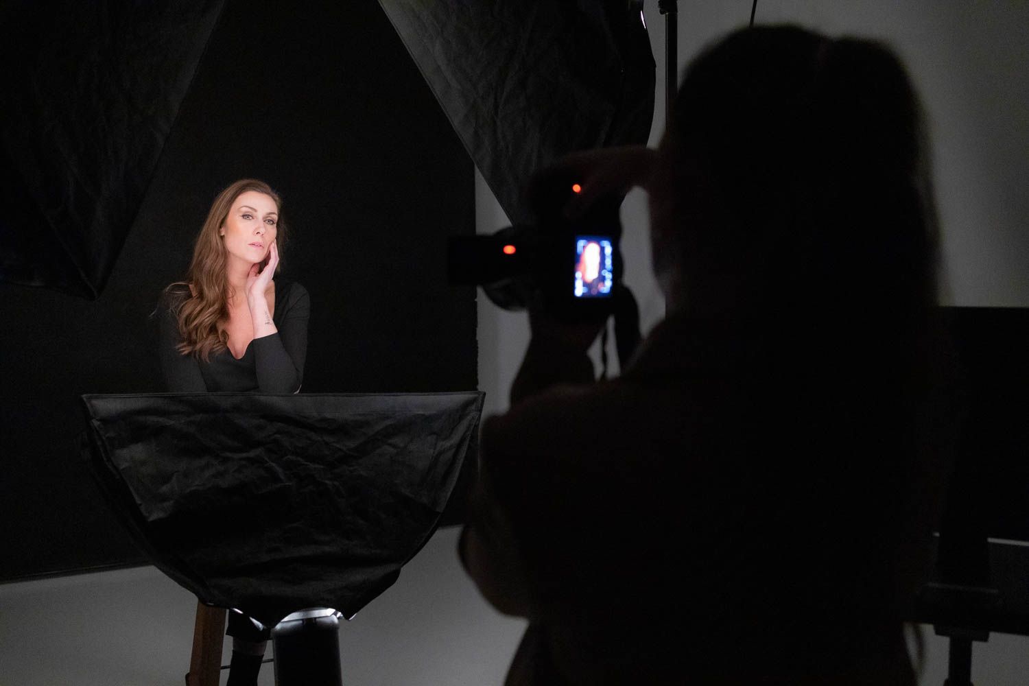 Professional photo studio setup with lighting equipment and monitors visible during a photography session.