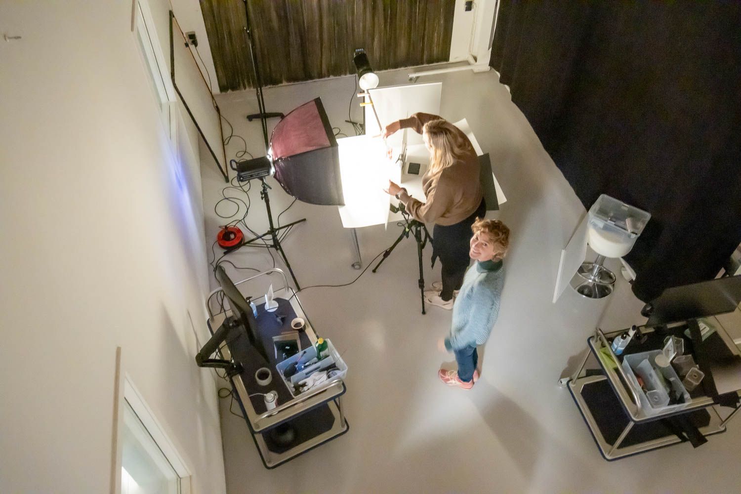 Professional makeup artist applying cosmetics to model in studio setting.