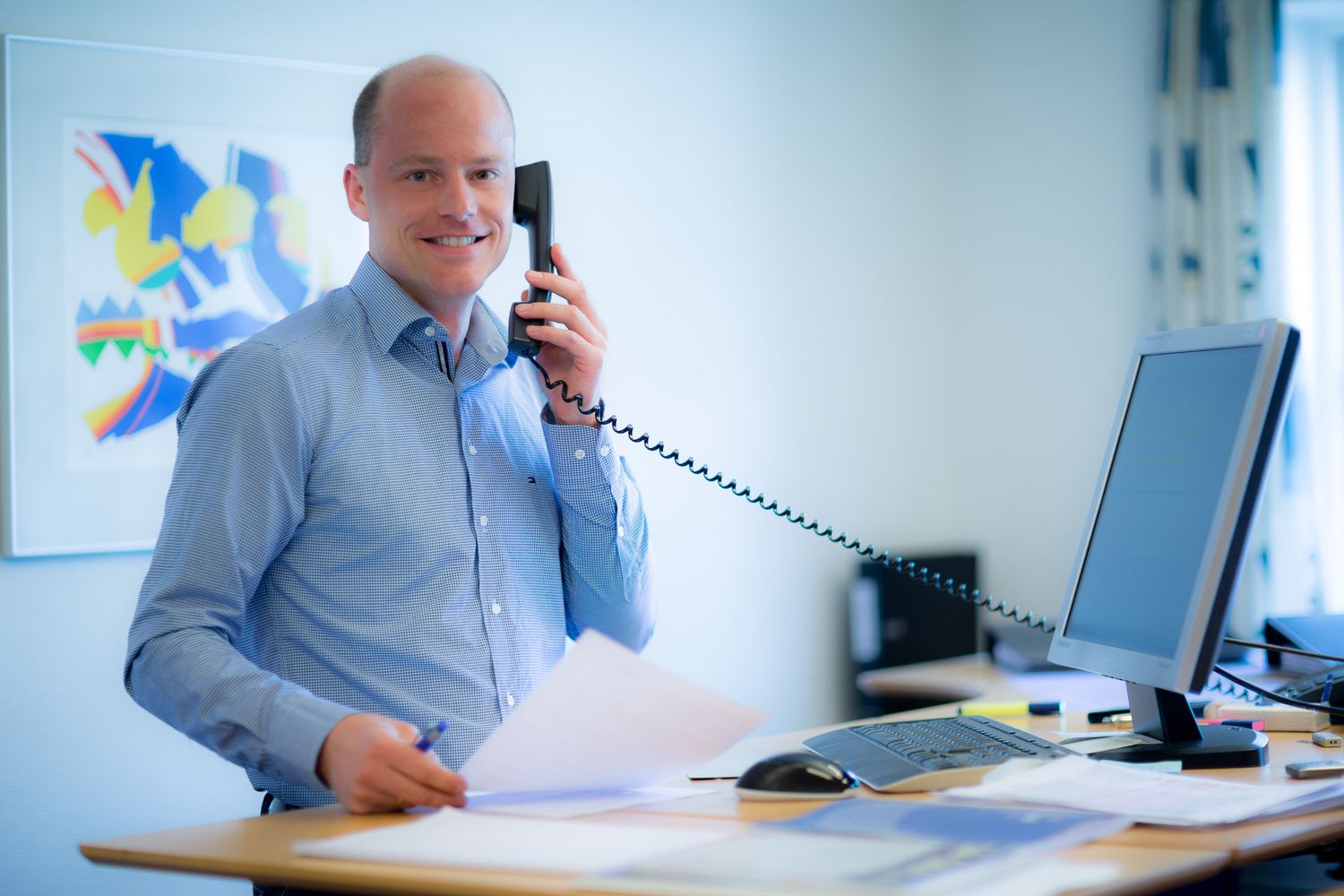 Employee talking on phone while working at desk in corporate office.