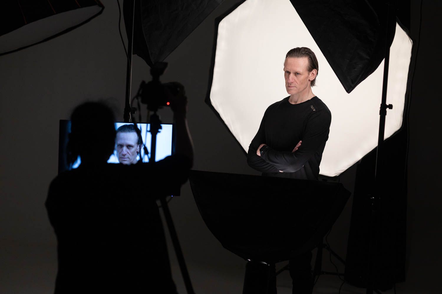 Studio photography session showing silhouettes of equipment and lighting setup against white backdrop.