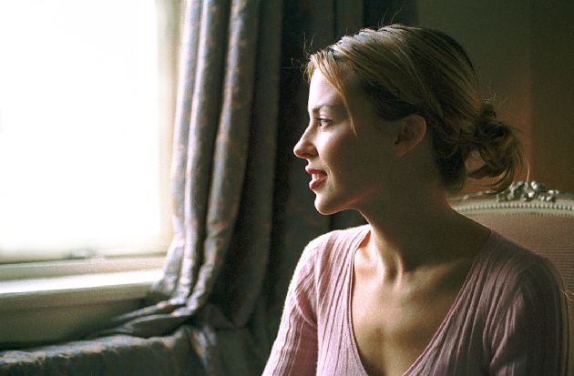 Side profile portrait near a window with natural lighting and curtains.