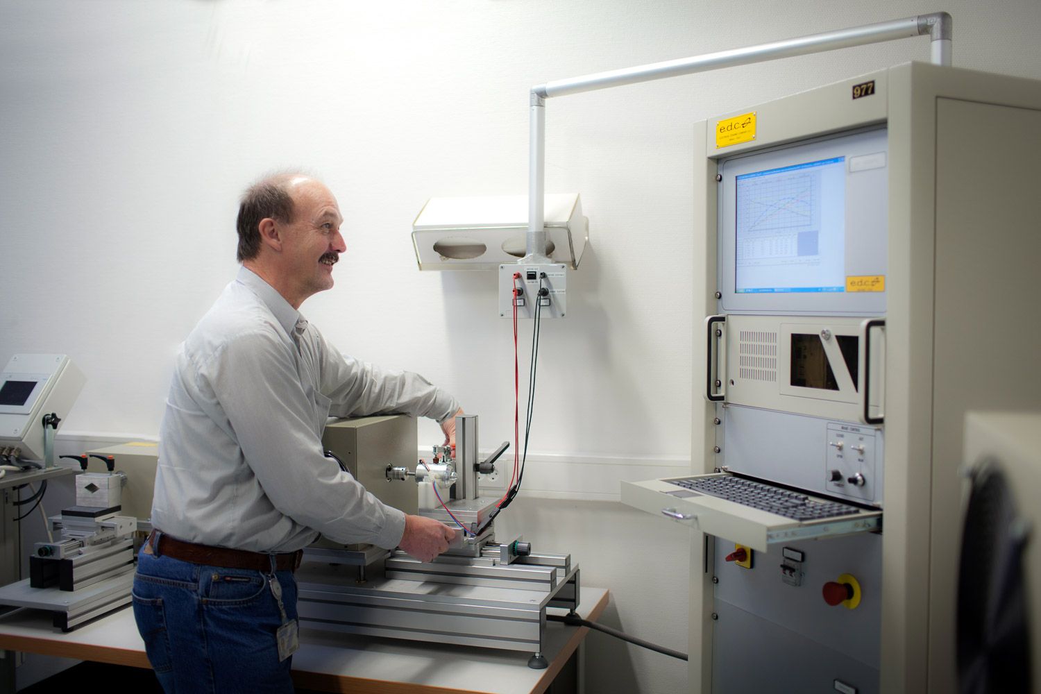 Laboratory technician operating precision measurement equipment in a clean testing facility.