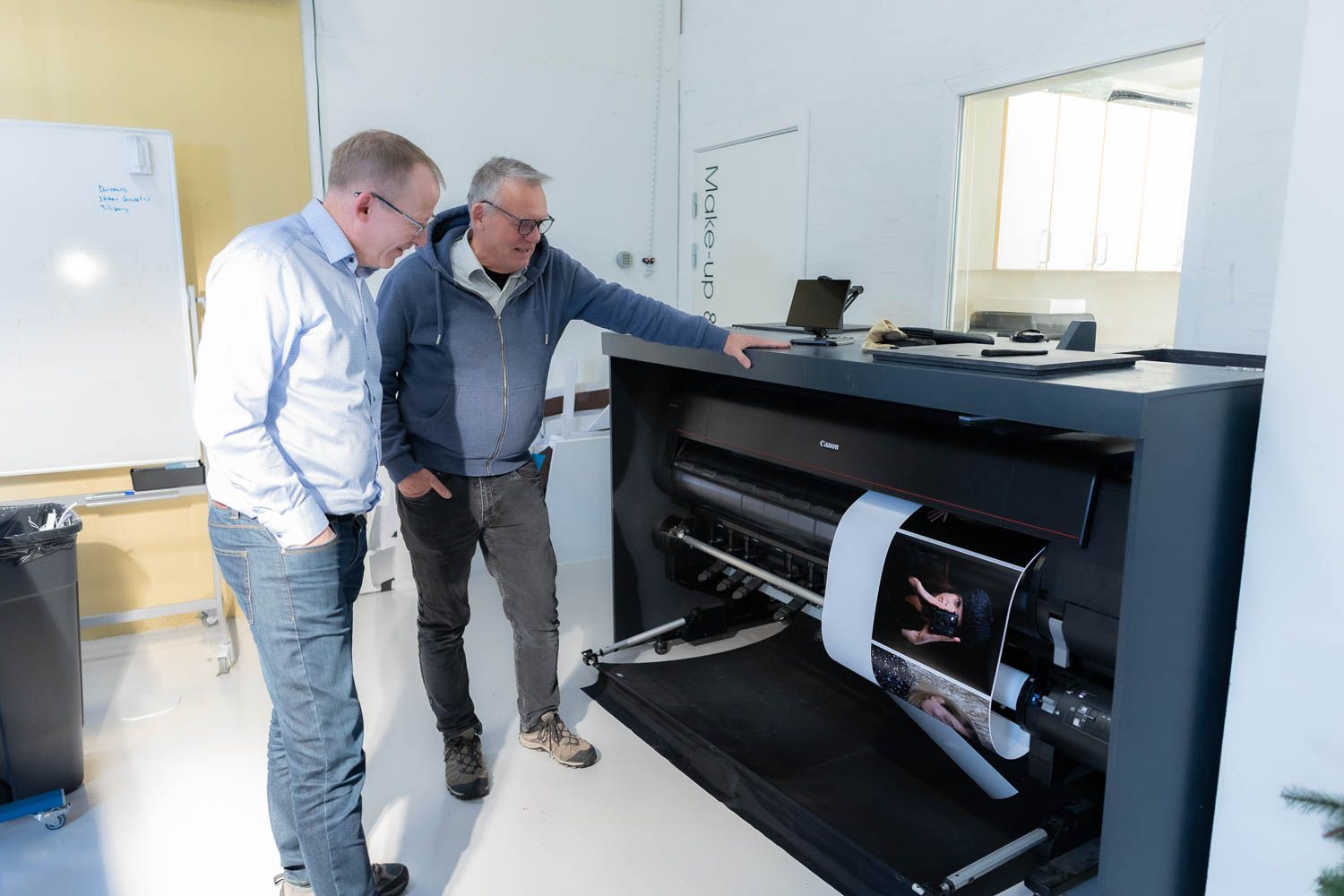 People examining large format prints in a bright office space.