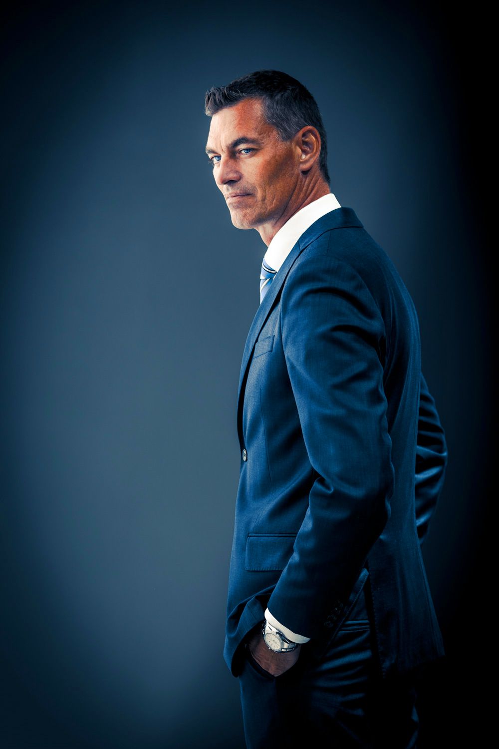 Professional business portraits in navy suit with dramatic studio lighting.