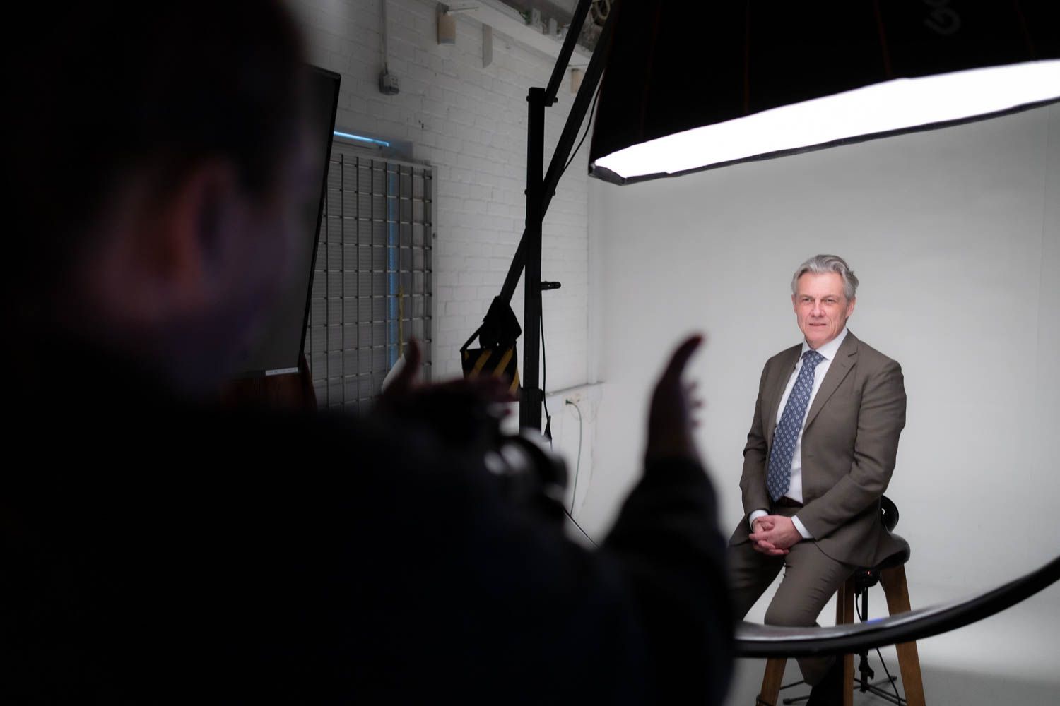 Behind-the-scenes view of a photography studio setup with lighting equipment and white backdrop.