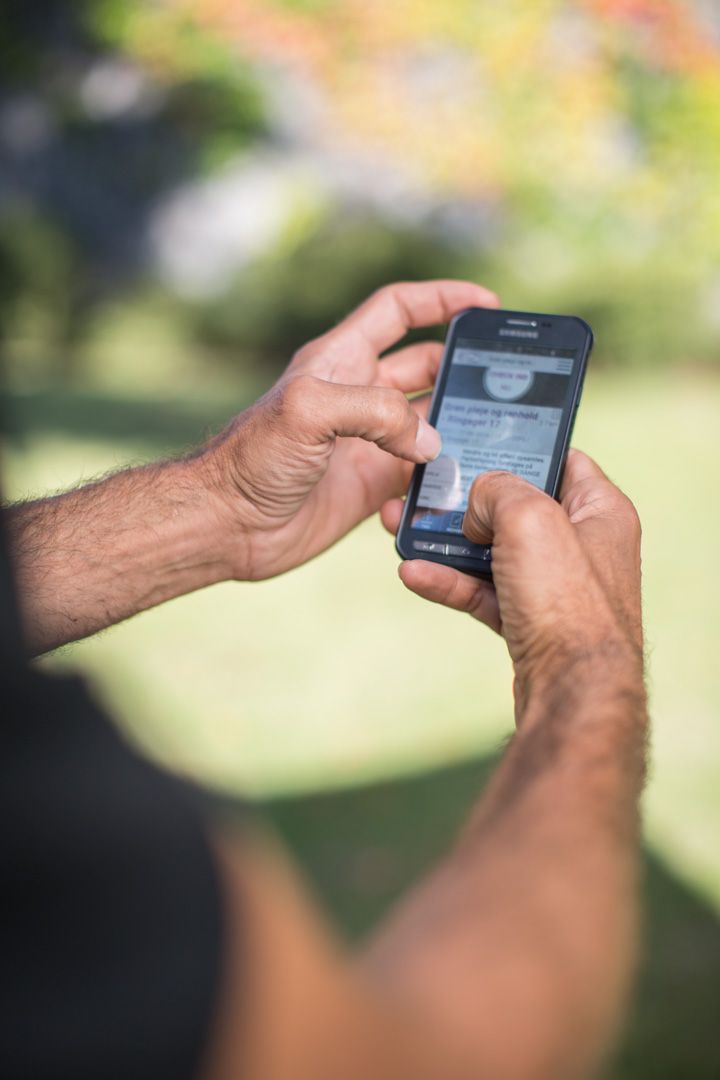 Hands holding smartphone displaying digital controls outdoors.