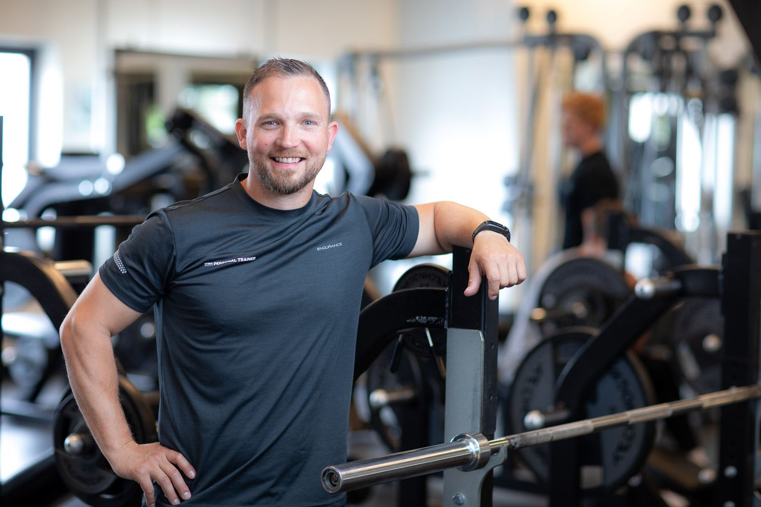 Person working out in a gym with exercise equipment and machines in the background.