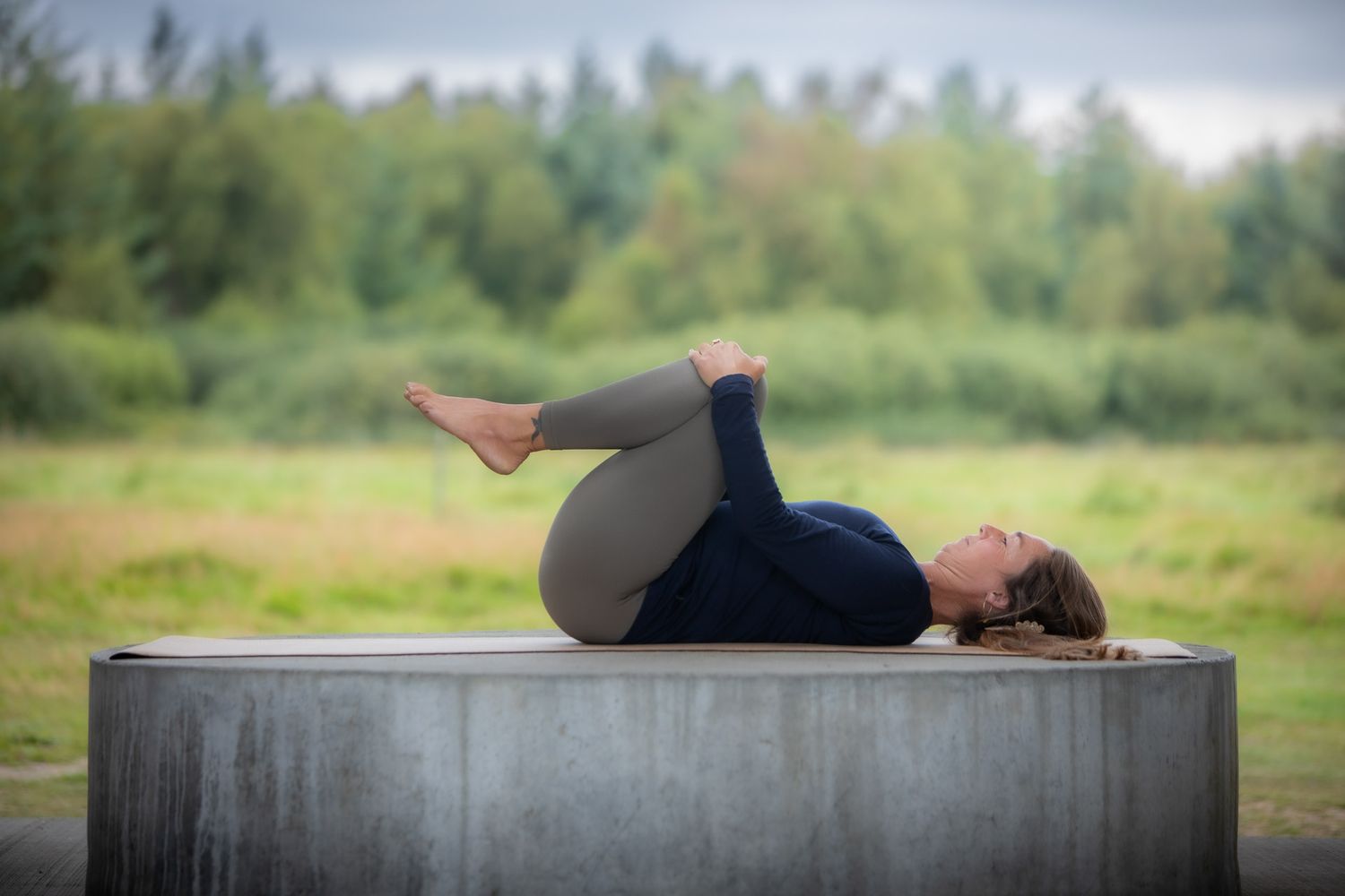 Person lying in relaxation pose on concrete surface outdoors.