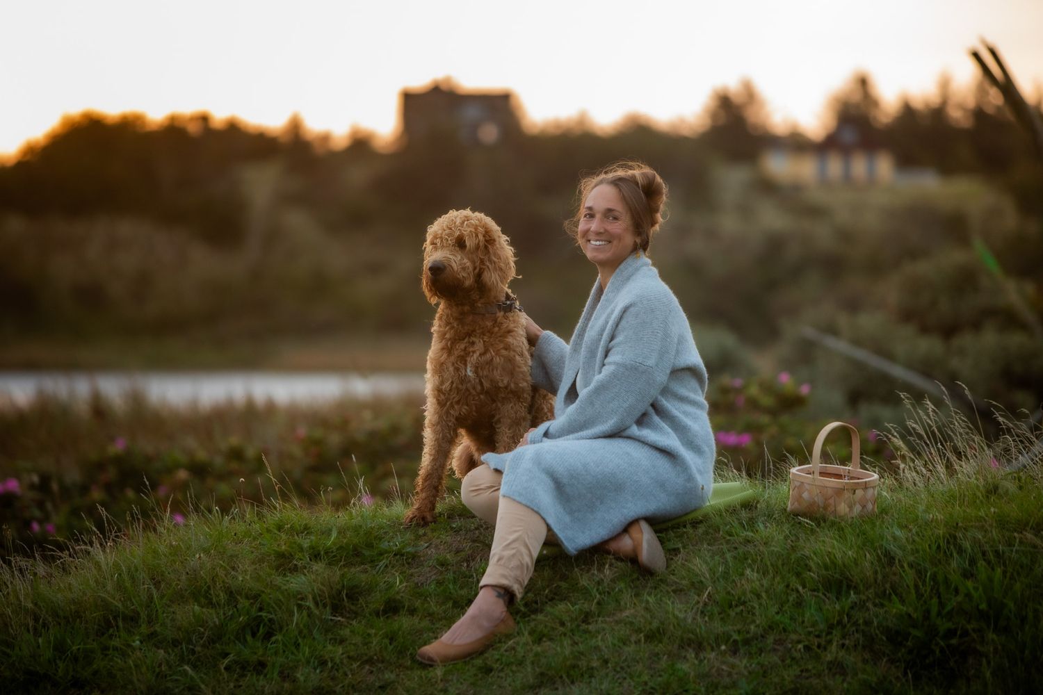 Enjoying a peaceful moment with a dog on a grassy hillside at sunset.