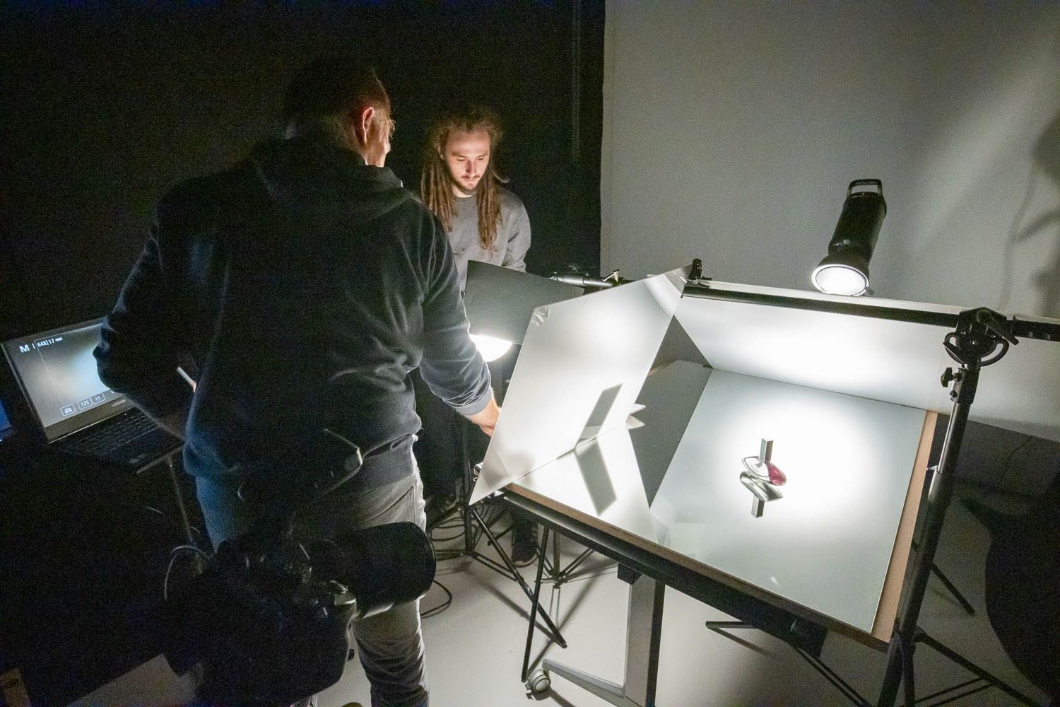 Photography studio workspace showing lighting equipment and reflectors during a shoot.