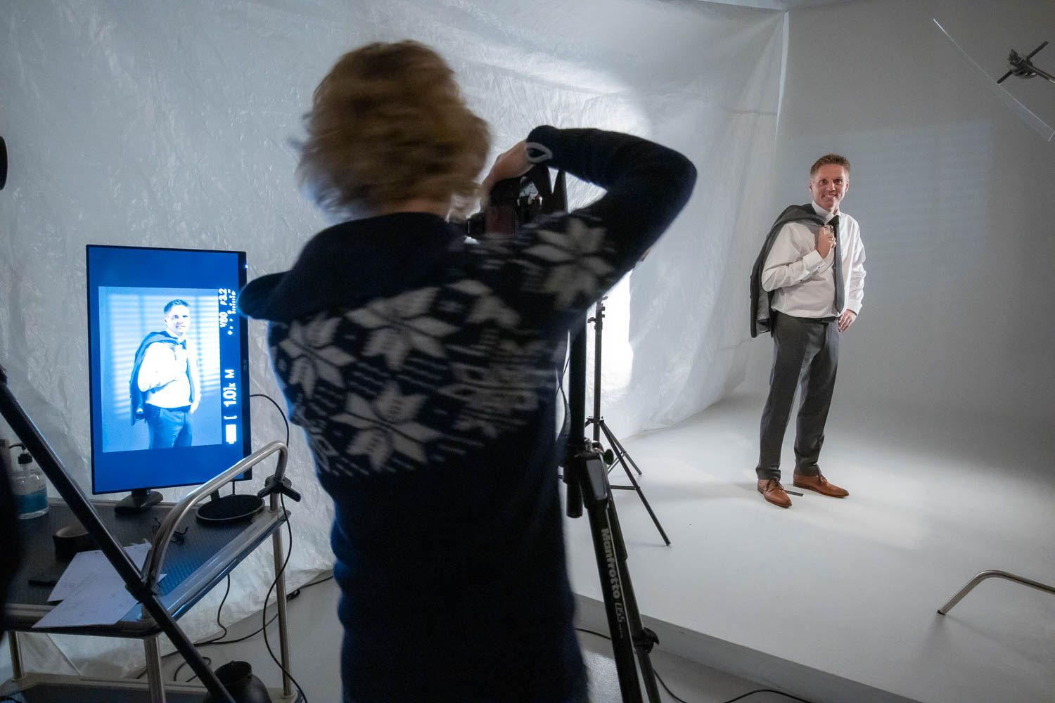 Professional photography studio setup with lighting equipment and white backdrop during a photo shoot session.