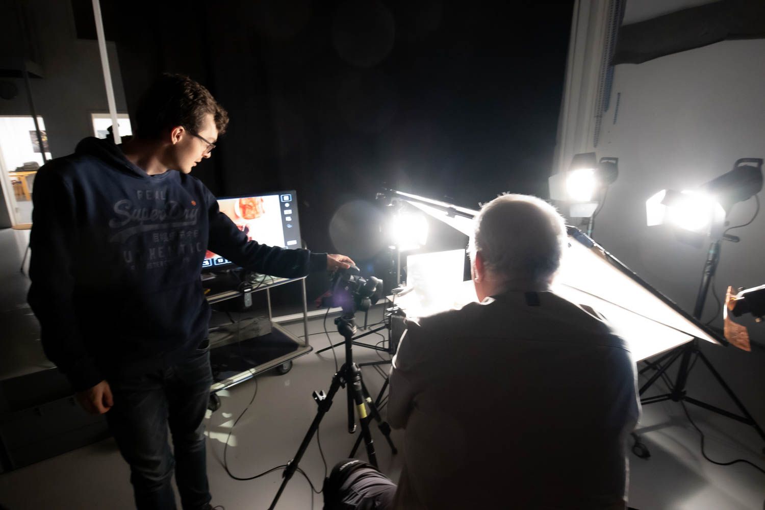 Silhouetted photography crew working in dimly lit studio with lighting equipment.