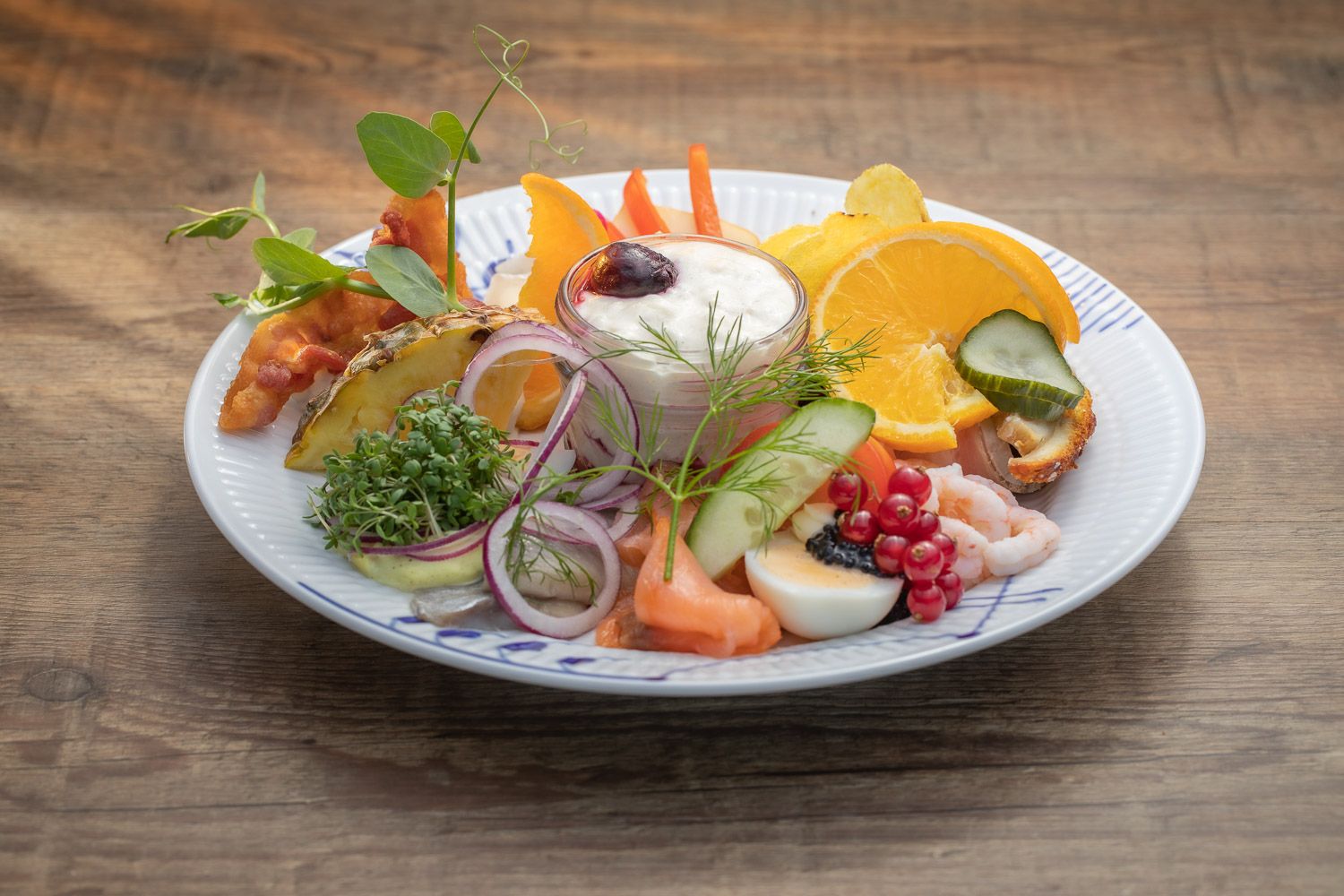 Colorful salad plate with citrus, vegetables and garnishes on white dish.