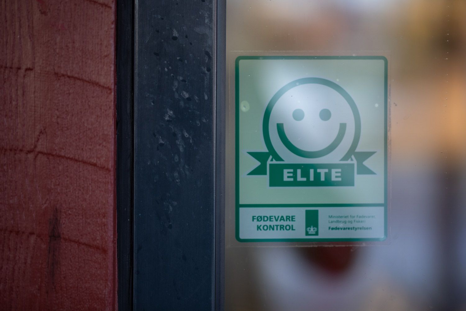 Elite certification sticker with smiley face logo displayed on window.