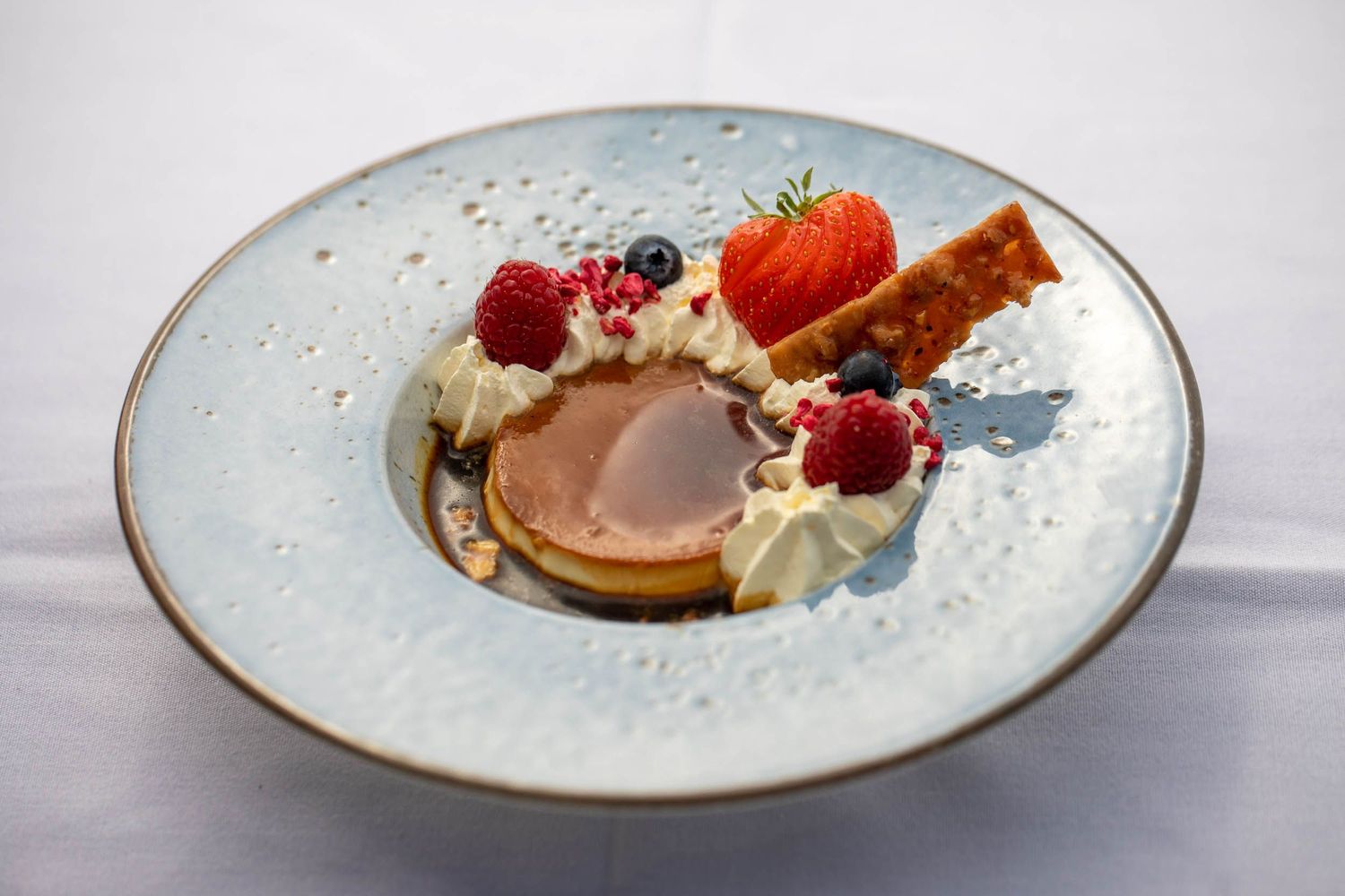 Elegant dessert plate with chocolate mousse, whipped cream, fresh berries and wafer garnish.