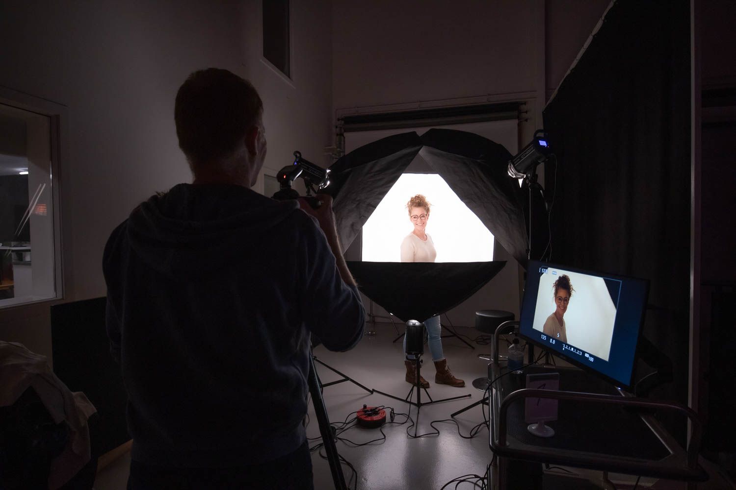 Photography studio setup showing monitors and circular lighting equipment during portrait session.