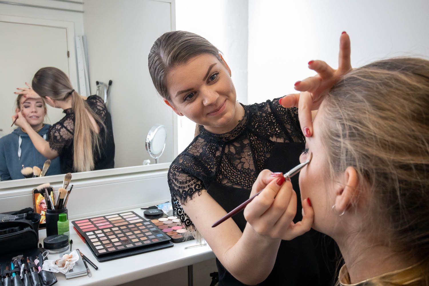 Makeup artist working on model's face in professional studio environment.