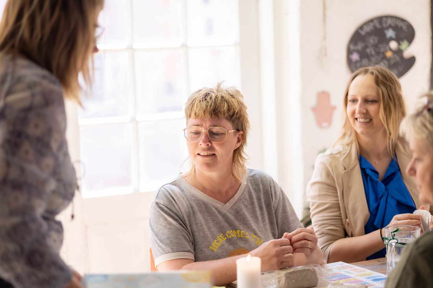 A group gathers around a table in a bright room during a casual meeting or workshop.
