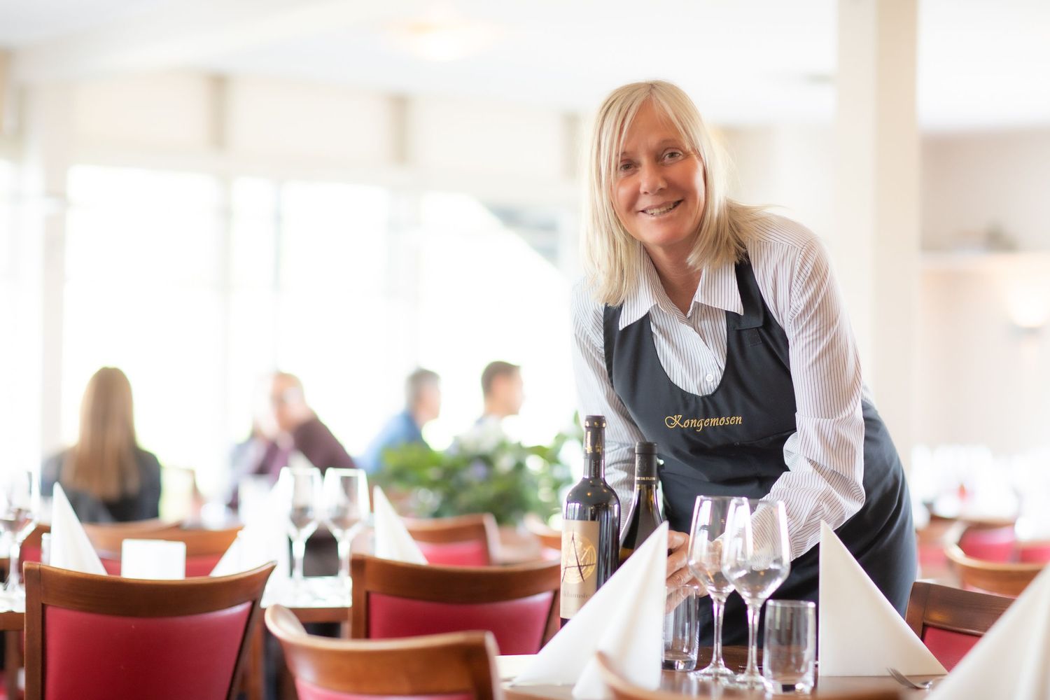 Restaurant staff setting tables and preparing for service.
