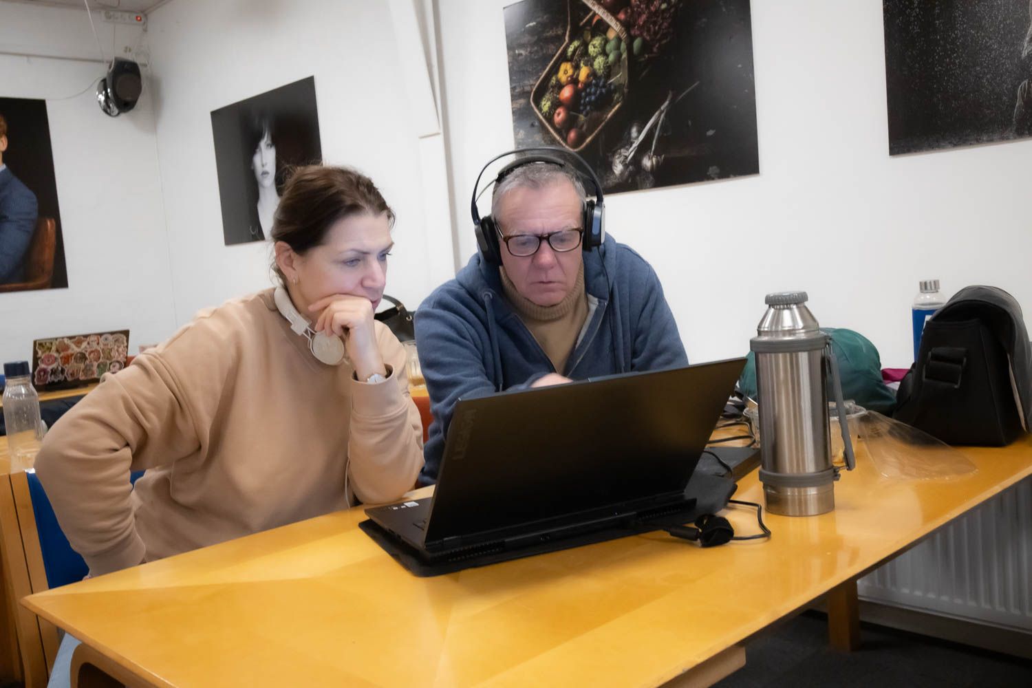 Several people collaborating around a wooden table with laptops and office supplies.