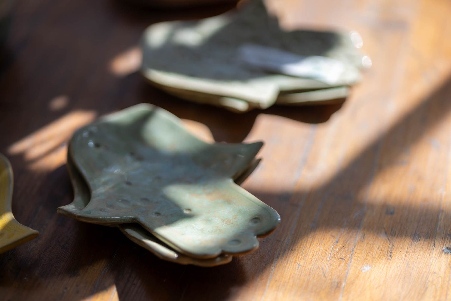 Ceramic pieces casting shadows on a wooden surface in artistic lighting.