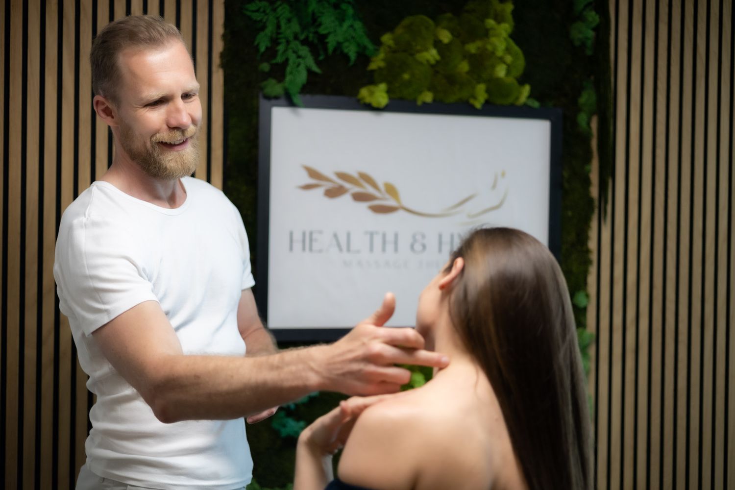 Massage therapist performs therapeutic neck massage treatment on client in wellness spa setting.