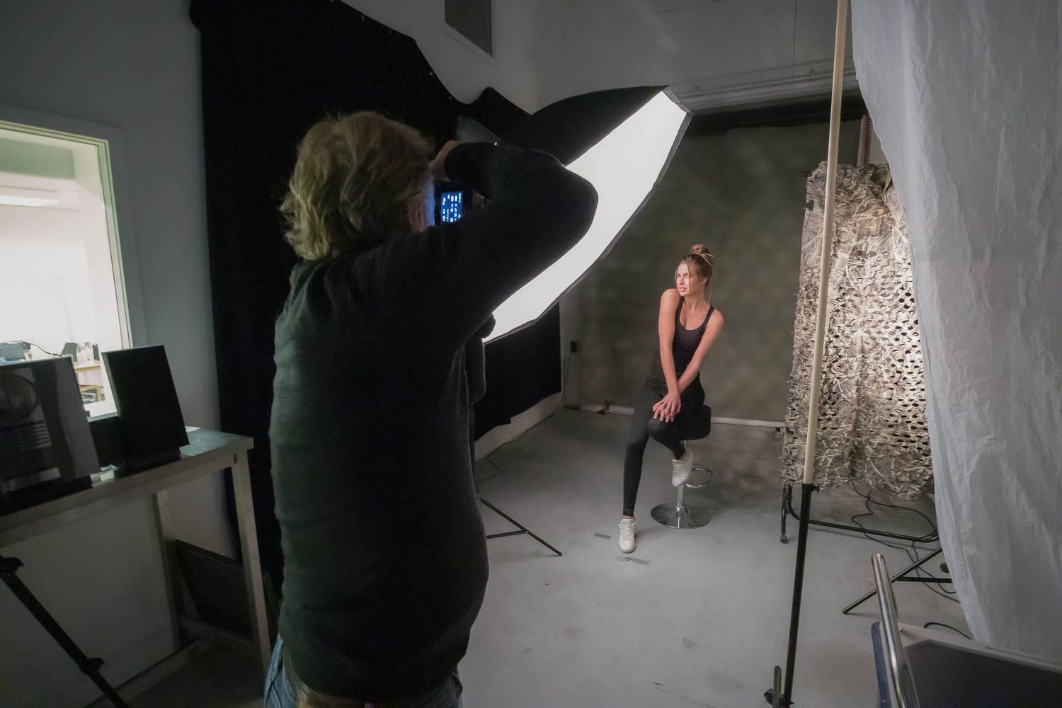 Professional photo studio setup with lighting equipment and diffusers arranged around a backdrop.