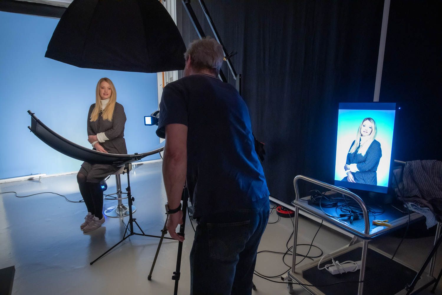 Photography studio setup with lighting equipment and monitor displaying image.