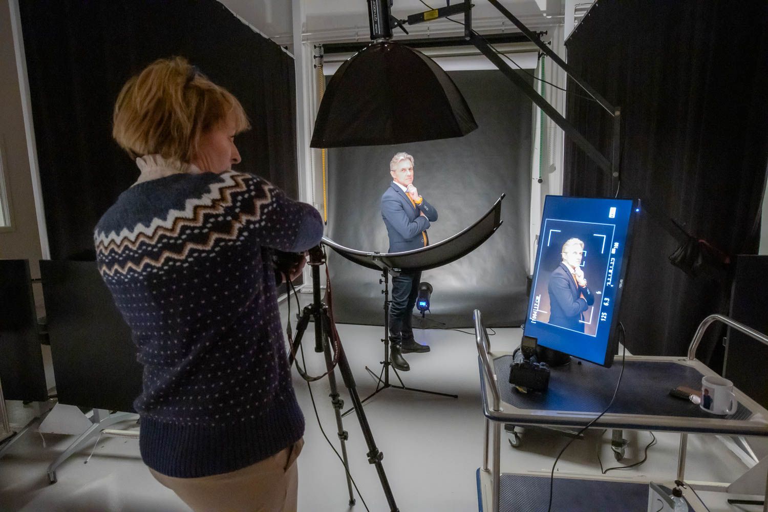 Behind the scenes view of photographers working in studio with lighting and camera equipment.