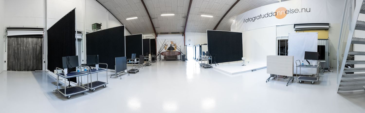 Clean white photography studio space with computers and professional equipment setup.