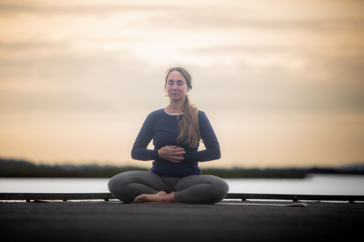 Peaceful meditation session on a wooden dock during golden hour.
