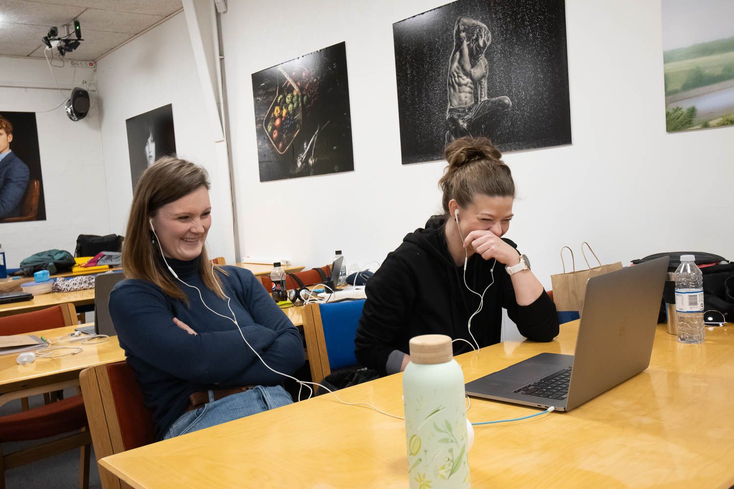 People working together at a conference table with laptops and drinks in a bright office space.